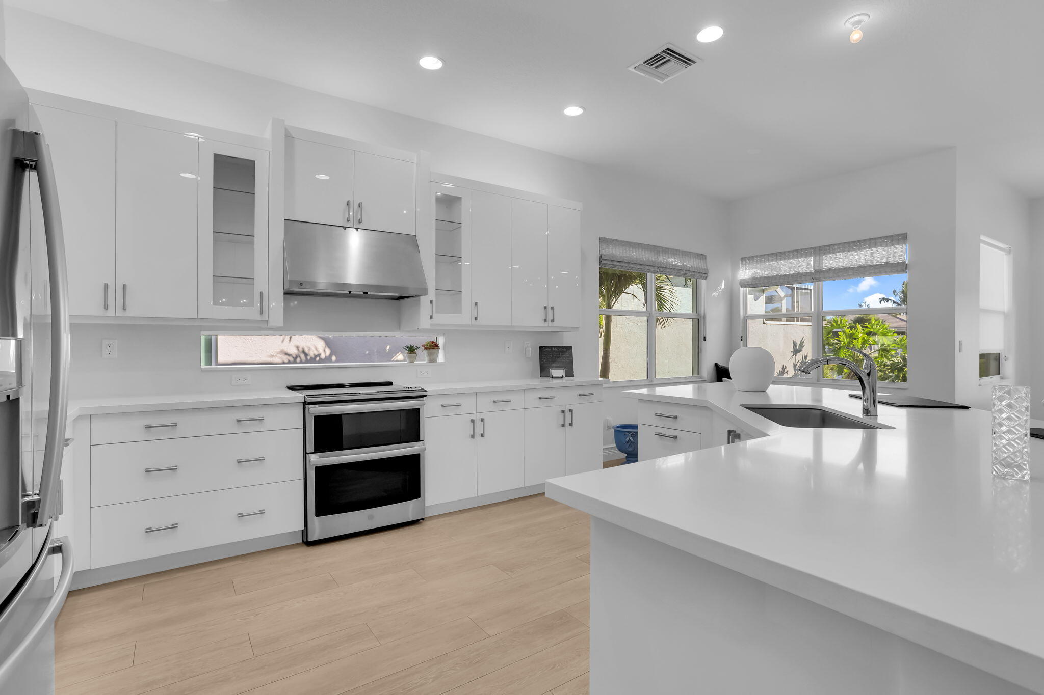 8254 Appalachian Ridge Road Boynton Beach, FL 33473 - Photo 9 of 50 a kitchen with stainless steel appliances a stove a sink a refrigerator a window and white cabinets with wooden floor