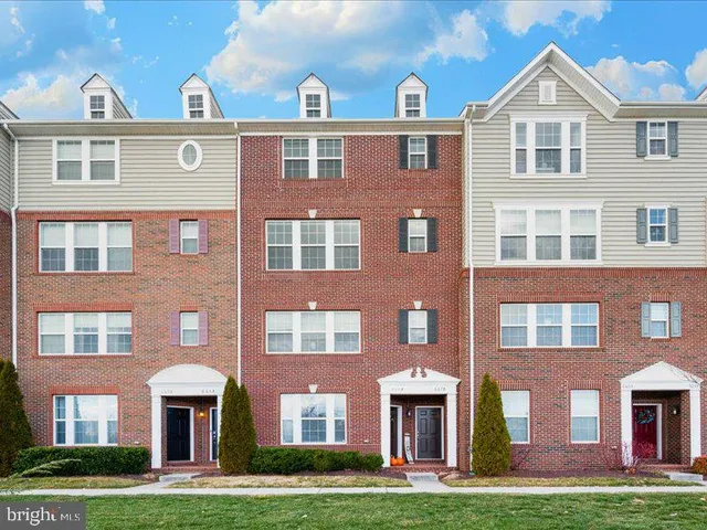 a front view of residential houses with yard and large trees