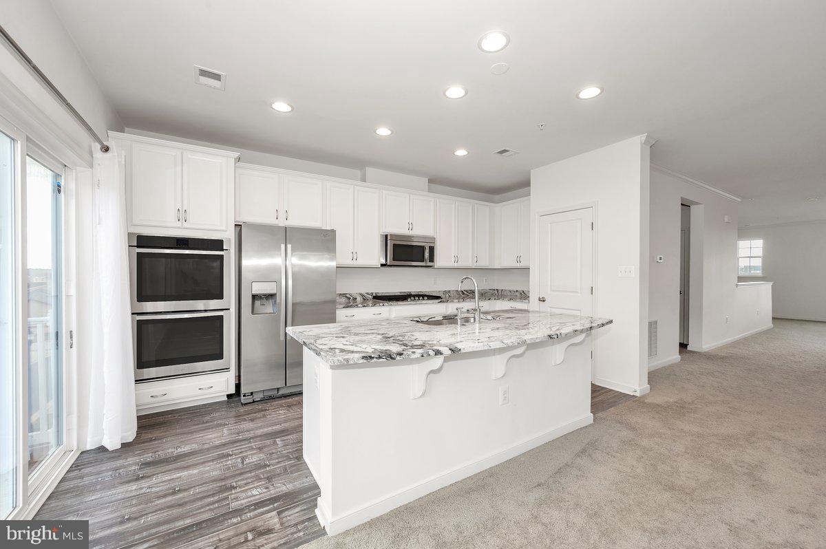667 East Church Street, Unit B Frederick, MD 21701 - Photo 3 of 51 a kitchen with stainless steel appliances kitchen island granite countertop a stove a refrigerator and a microwave
