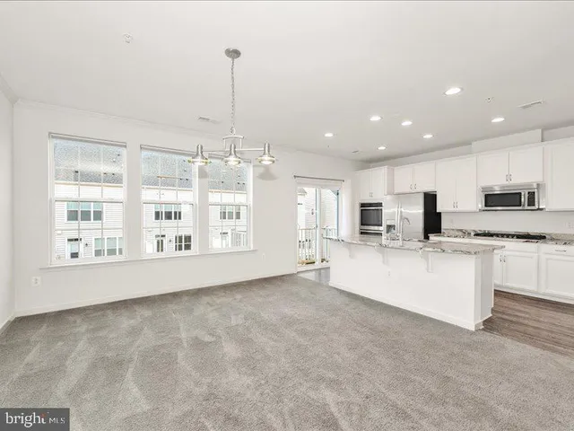 a view of kitchen with stainless steel appliances granite countertop a stove top oven a sink and a chandelier