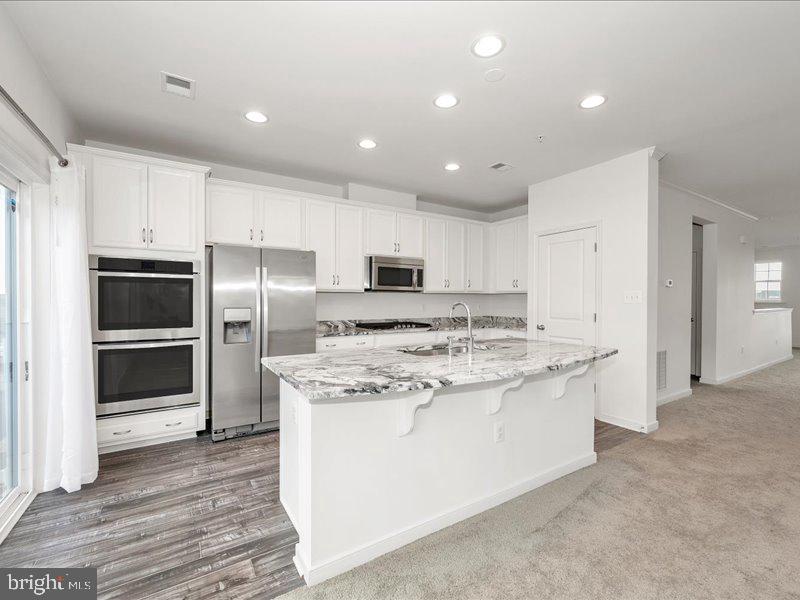 667 East Church Street, Unit B Frederick, MD 21701 - Photo 9 of 51 a kitchen with stainless steel appliances kitchen island granite countertop a stove a refrigerator and a sink