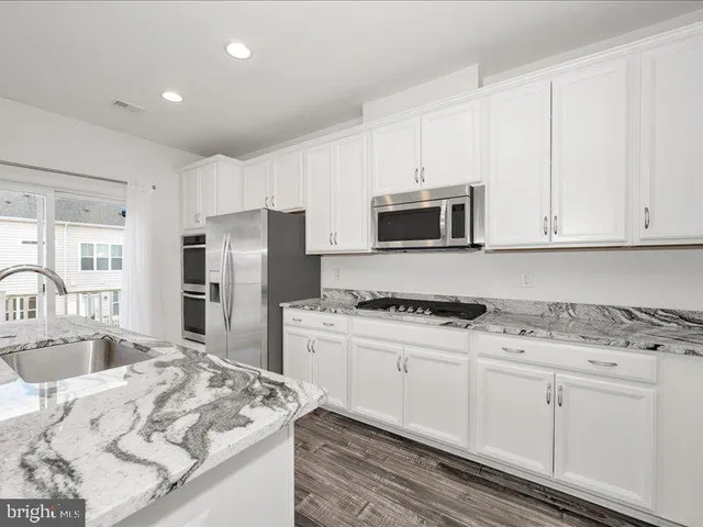 a kitchen with granite countertop a sink stove and refrigerator