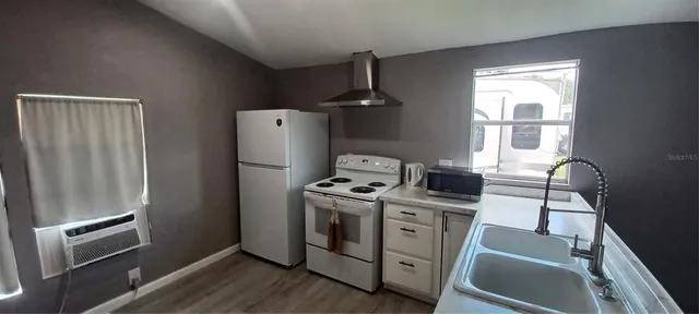 a view of a kitchen with refrigerator and wooden floor