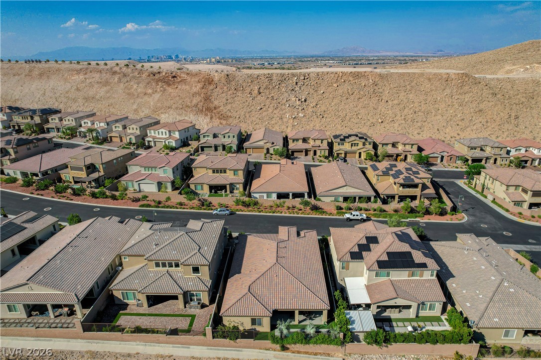 3943 Reyes Avenue Las Vegas, NV 89141 - Photo 68 of 95 An aerial perspective reveals a modern residential development nestled against a desert hillside, offering distant city views.