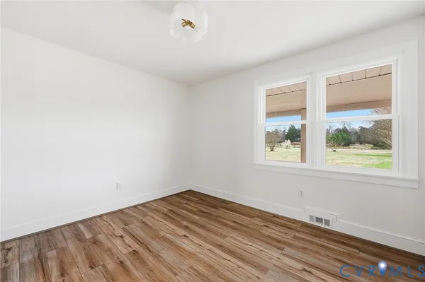 an empty room with wooden floor ceiling fan and windows