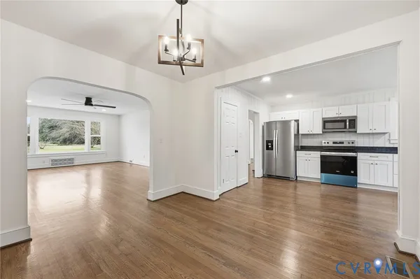 an empty room with wooden floor fireplace and windows