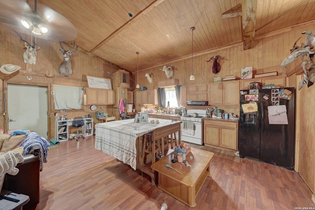 1443 Gina Road Harper, TX 78631 - Photo 9 of 49 a large room with kitchen island a stove a refrigerator a sink dishwasher a dining table and chairs with wooden floor
