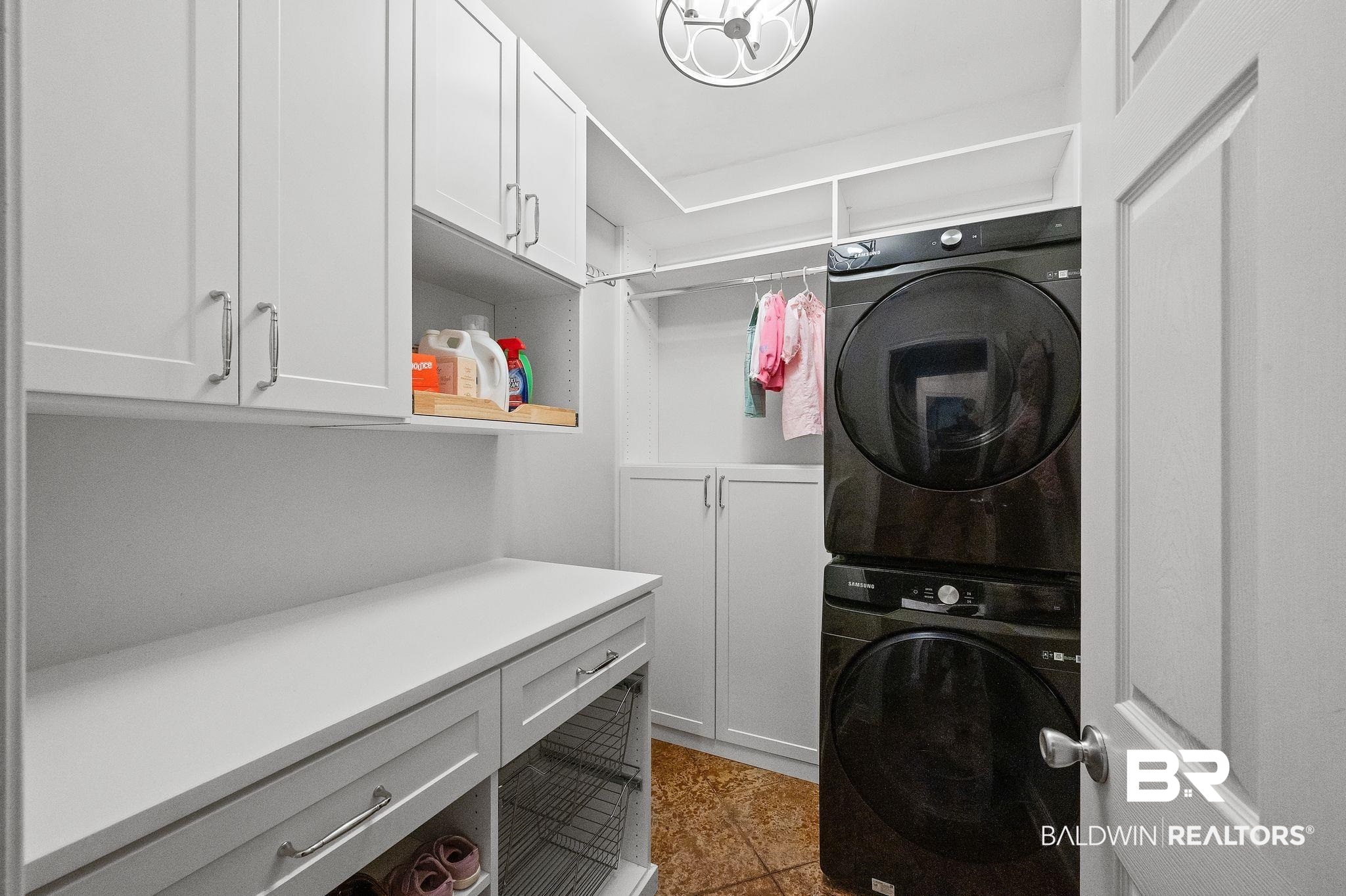 1825 Spring Hill Avenue Mobile, AL 36607 - Photo 32 of 43 Washroom featuring estacked washer and dryer, cabinet space, and dark tile patterned floors