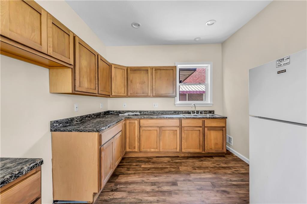 522 Jefferson Street Rochester, PA 15074 - Photo 10 of 28 a kitchen with granite countertop a refrigerator a stove a sink and white cabinets