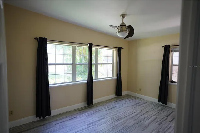 an empty room with wooden floor cabinet and windows