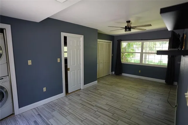 a view of an empty room with a window and wooden floor