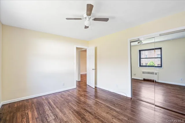 an empty room with wooden floor chandelier fan and windows