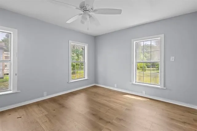 a view of an empty room with a window and wooden floor