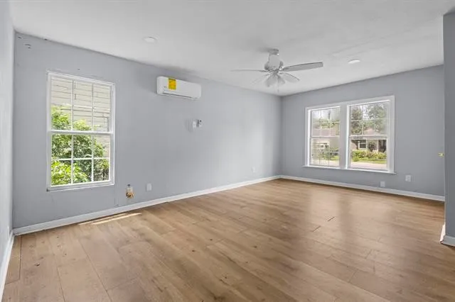 an empty room with windows and ceiling fan