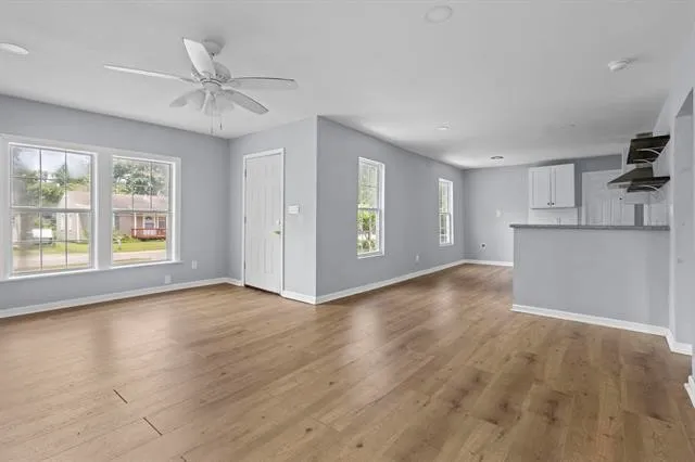 a view of an empty room with a window and wooden floor