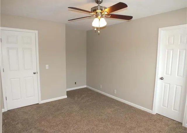 an empty room with a fan & a window