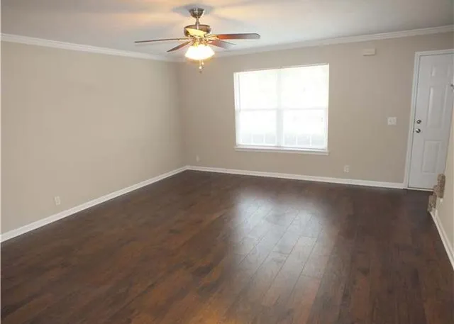 an empty room with wooden floor fan and windows