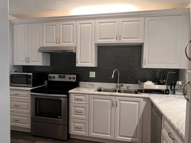 a kitchen with granite countertop a stove sink and cabinets