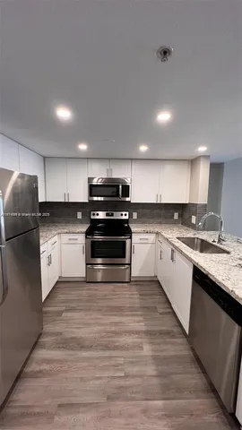 a large kitchen with cabinets wooden floor and stainless steel appliances