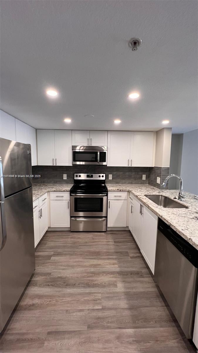 218 Northwest 12th Avenue, Unit 905 Miami, FL 33128 - Photo 3 of 15 a large kitchen with cabinets wooden floor and stainless steel appliances