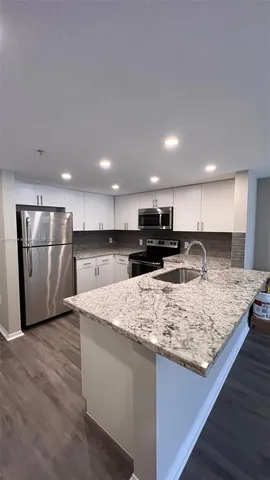 a large kitchen with kitchen island a stove a refrigerator counter top oven and cabinets