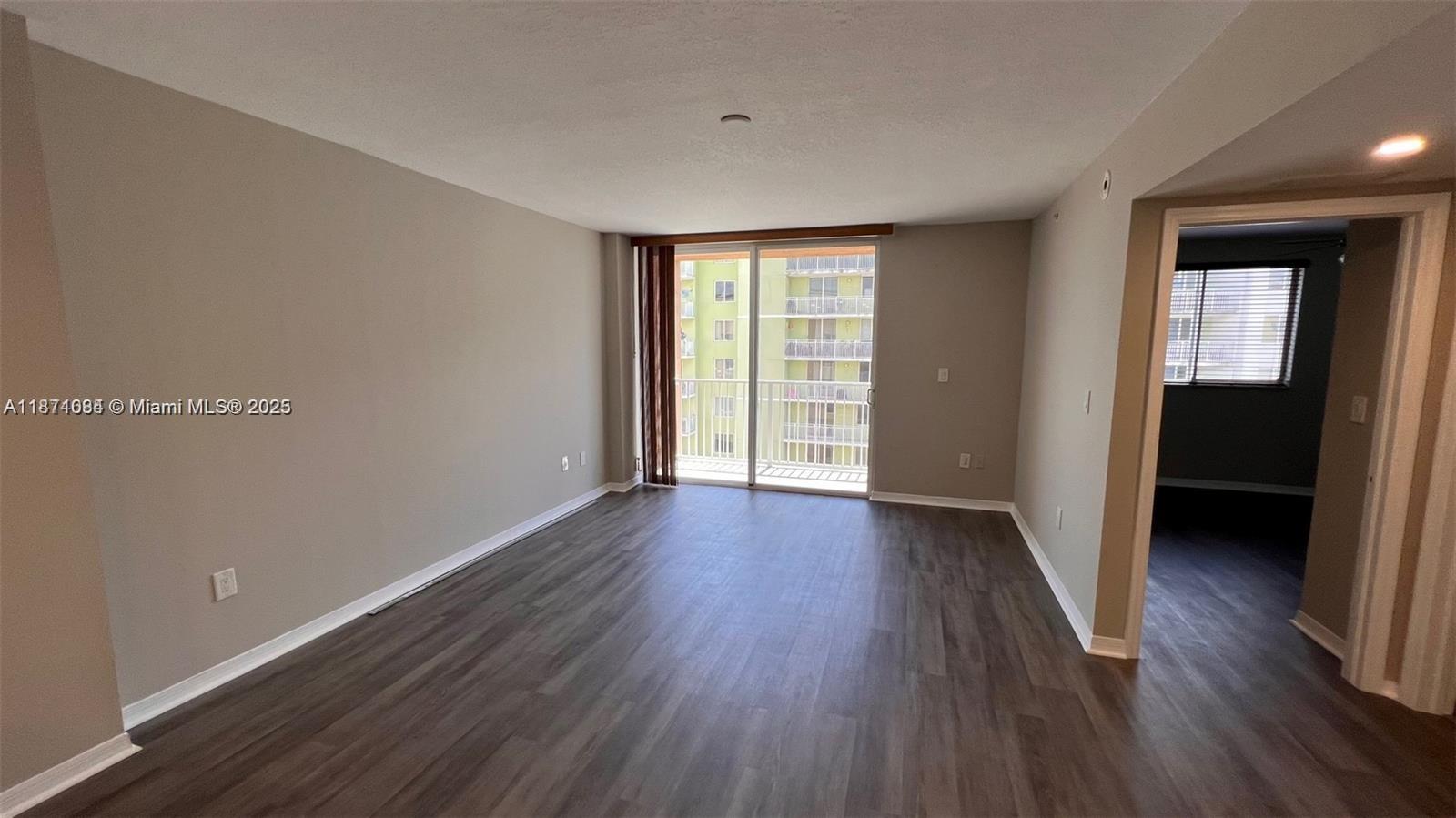 218 Northwest 12th Avenue, Unit 905 Miami, FL 33128 - Photo 5 of 15 a view of an empty room with wooden floor and a window