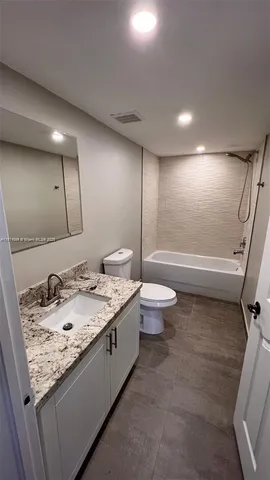 a bathroom with a granite countertop sink a toilet and a large mirror