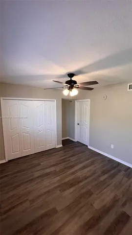 a view of empty room with wooden floor and ceiling fan