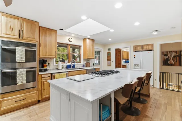 a kitchen with stainless steel appliances kitchen island granite countertop a kitchen island and chairs in it