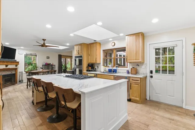 a room with stainless steel appliances kitchen island granite countertop a stove a sink a dining table and chairs