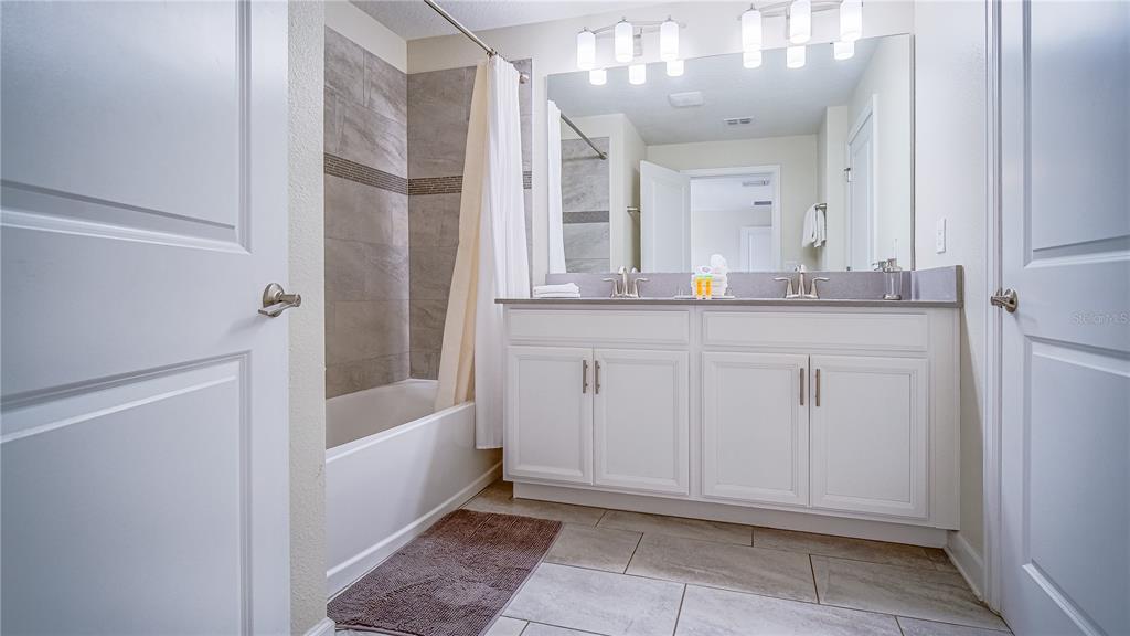 8919 Stinger Drive Davenport, FL 33896 - Photo 14 of 39 a bathroom with a granite countertop sink a mirror and a bathtub