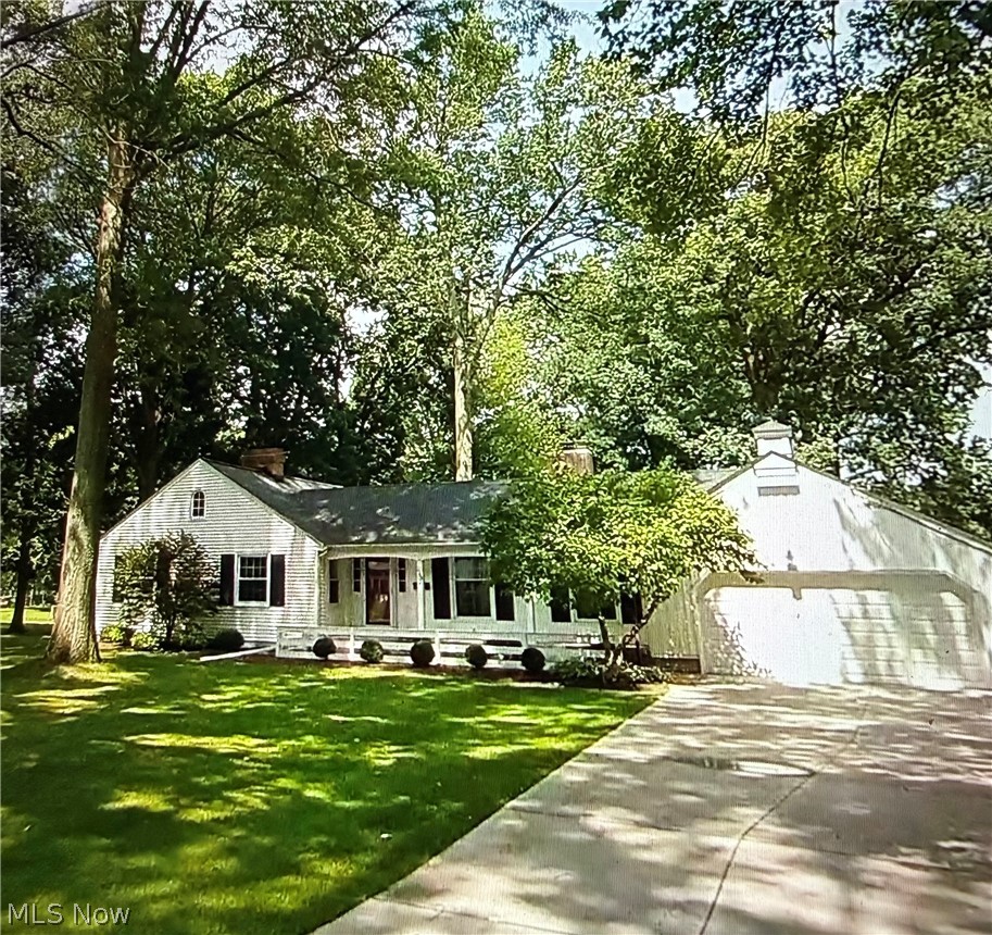 145 Overlook Road Painesville, OH 44077 - Photo 1 of 36 View of front of property with a porch, a front yard, concrete driveway, a garage, and view of scattered trees