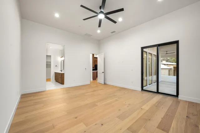 a view of empty room with wooden floor and ceiling fan