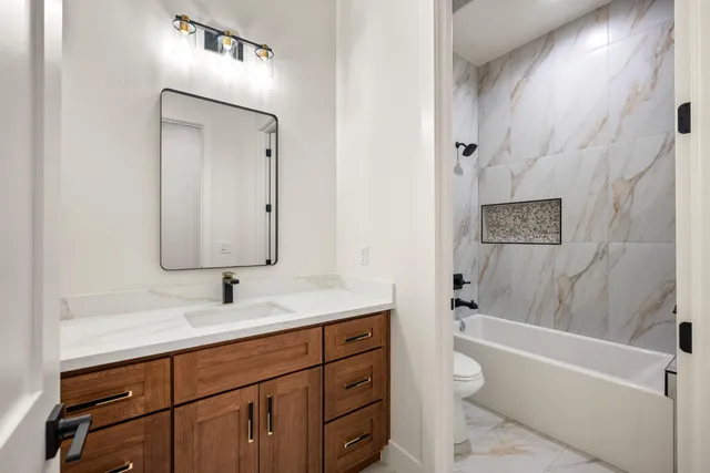 a bathroom with a toilet a sink a tub and mirror