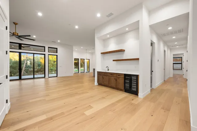 a view of an empty room and kitchen with furniture wooden floor and a large window