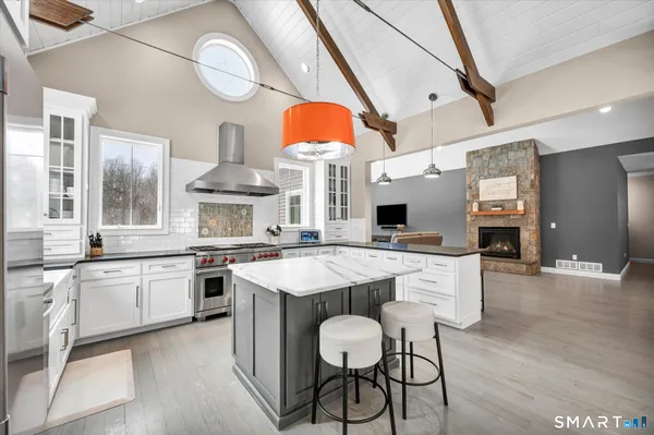 a kitchen with stainless steel appliances a stove a sink dishwasher and a fireplace with wooden floor