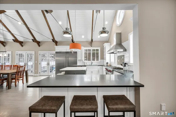 a kitchen with stainless steel appliances a dining table chairs and wooden floor