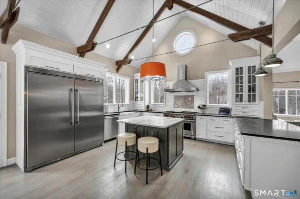 a kitchen with stainless steel appliances granite countertop a kitchen island a stove a table and chairs in it