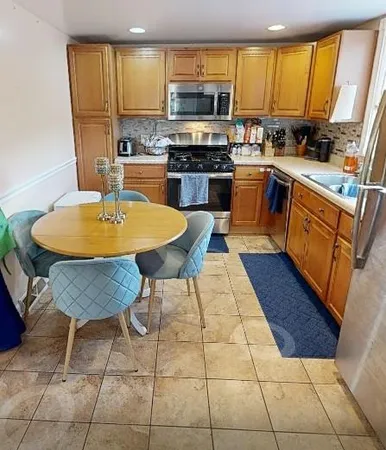 a kitchen with stainless steel appliances a stove a sink a microwave a refrigerator a stove a sink a dining table and chairs