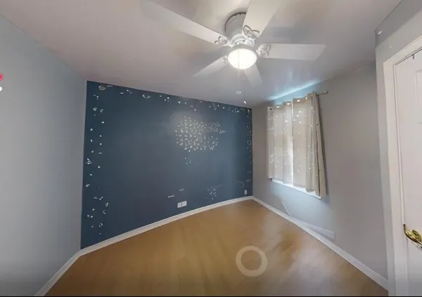 an empty room with windows and fan