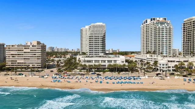 a kitchen with stainless steel appliances granite countertop a refrigerator a stove top oven a dining table and chairs with wooden floor