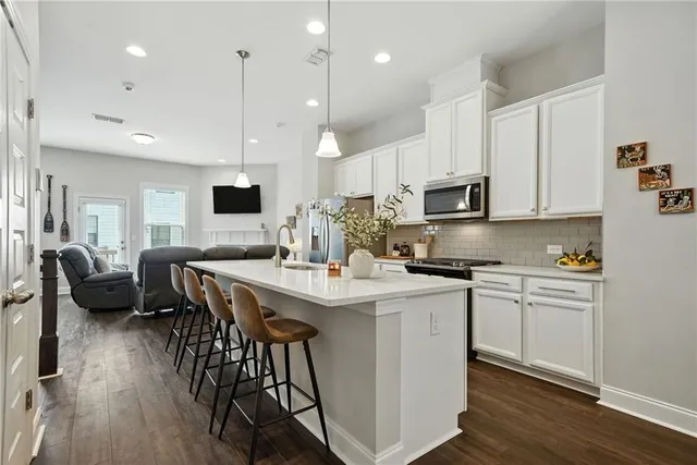 a kitchen with stainless steel appliances kitchen island granite countertop a stove a sink a microwave a center island and a cabinets