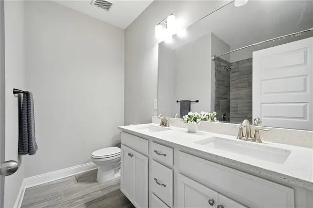 a bathroom with a double vanity sink toilet and a mirror