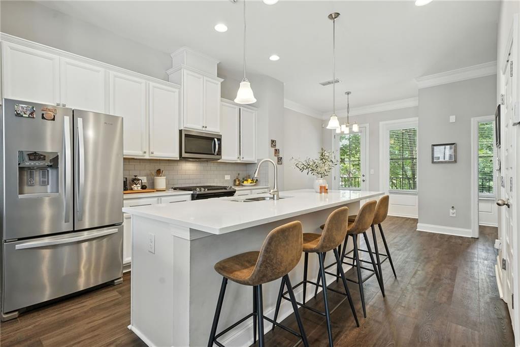 705 Bismark Road Northeast Atlanta, GA 30324 - Photo 3 of 41 a kitchen with stainless steel appliances a microwave a stove a refrigerator a sink a dining table and chairs with wooden floor