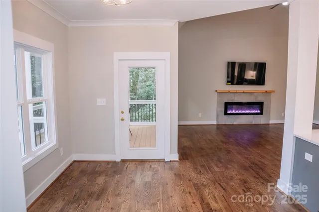 a view of an empty room with wooden floor fireplace and a window