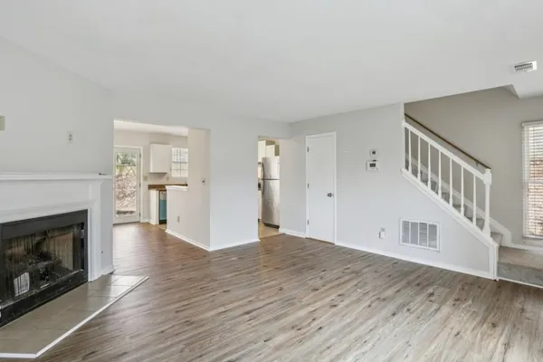 a view of an empty room with wooden floor fireplace and a window