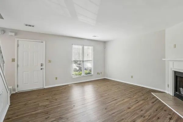 a view of an empty room with wooden floor and a window