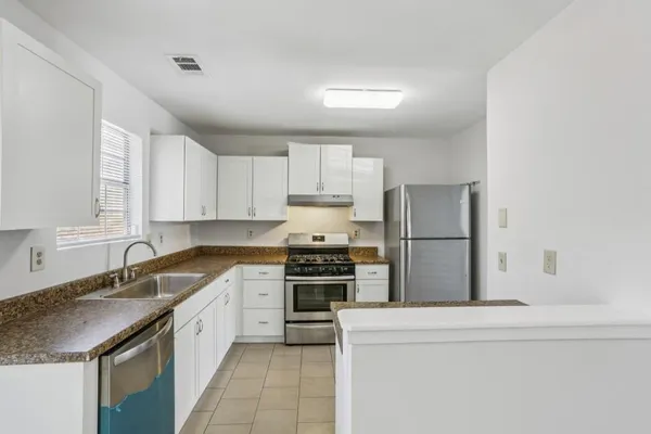 a kitchen with granite countertop a sink stove and refrigerator