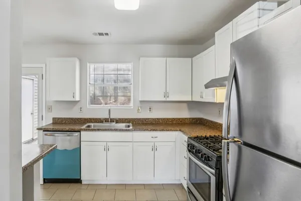 a kitchen with granite countertop a sink stove and refrigerator