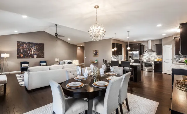 a view of a dining room and livingroom with furniture wooden floor a chandelier
